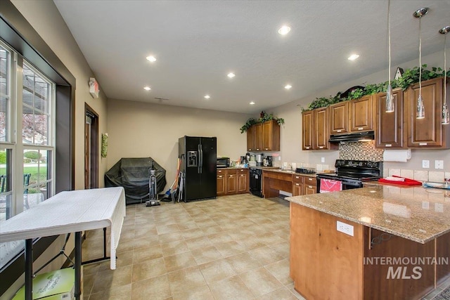 kitchen featuring a breakfast bar, pendant lighting, black appliances, light stone counters, and kitchen peninsula