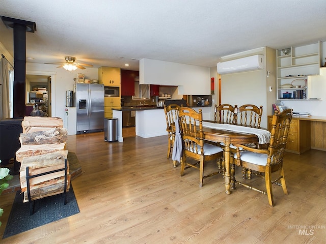 dining space featuring ceiling fan, light wood-type flooring, a wood stove, and an AC wall unit