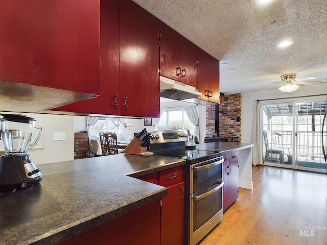 kitchen with double oven range, ceiling fan, a textured ceiling, and light wood-type flooring