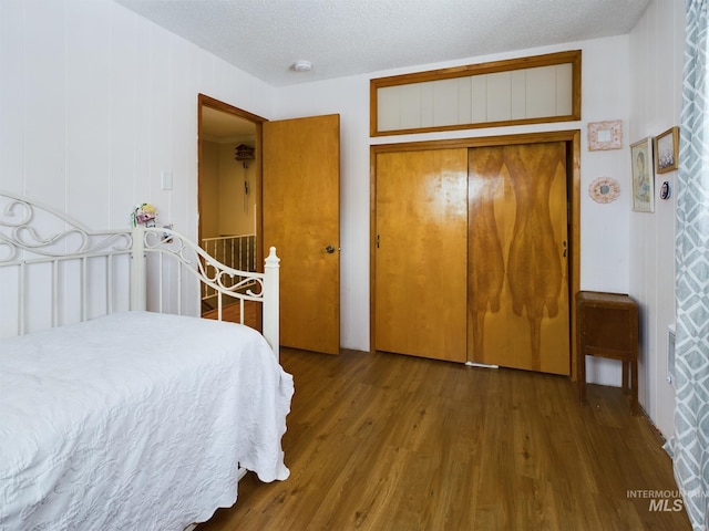 bedroom with hardwood / wood-style flooring, a textured ceiling, and a closet