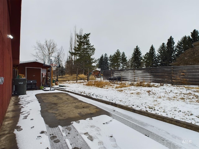 snowy yard featuring a playground