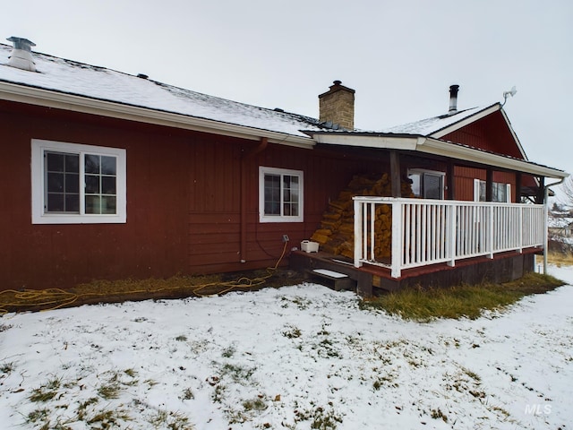 snow covered back of property with a porch