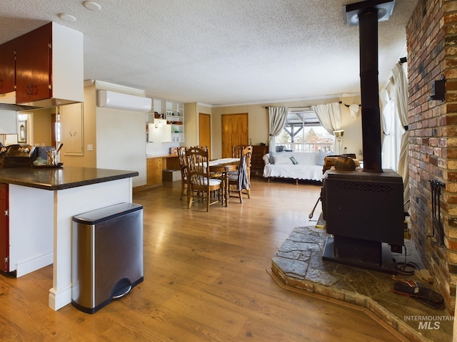 living room featuring hardwood / wood-style flooring, an AC wall unit, a wood stove, and a textured ceiling