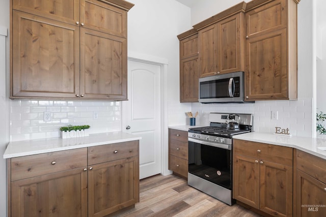 205 W 13th Ave, Jerome, ID 83338 - kitchen featuring appliances with stainless steel finishes, decorative backsplash, light wood-style floors, and light countertops