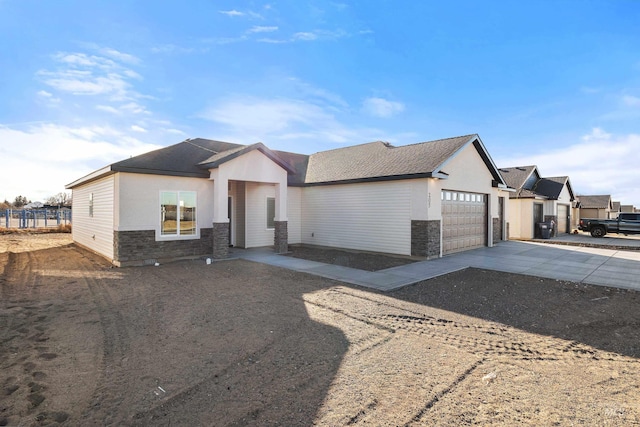205 W 13th Ave, Jerome, ID 83338 - view of front of house with concrete driveway, stone siding, an attached garage, and stucco siding
