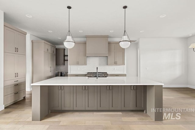 kitchen with decorative backsplash, gray cabinets, light hardwood / wood-style flooring, and a large island