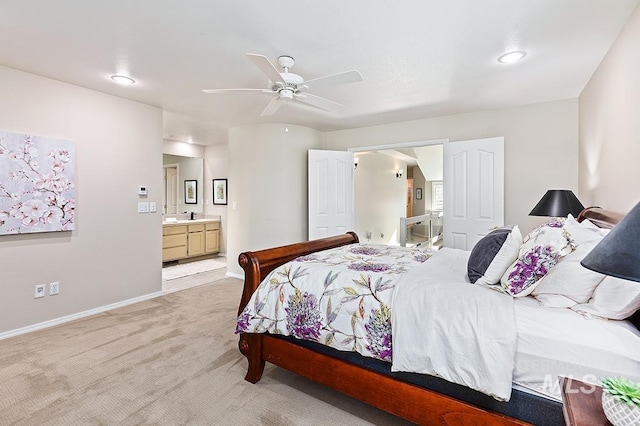 bedroom with a ceiling fan, light colored carpet, baseboards, and ensuite bathroom