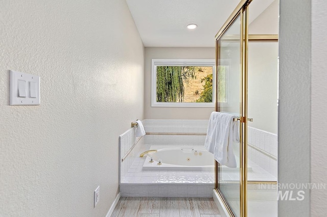 full bath featuring a tub with jets and a textured wall