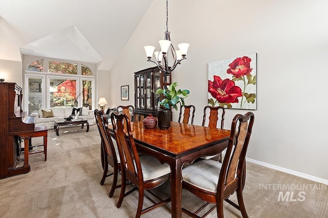 dining area with a chandelier, light colored carpet, high vaulted ceiling, and baseboards