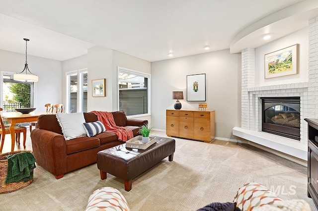 living area featuring light carpet, a brick fireplace, baseboards, and recessed lighting