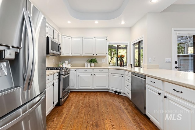 kitchen with stainless steel appliances, recessed lighting, light countertops, white cabinets, and wood finished floors