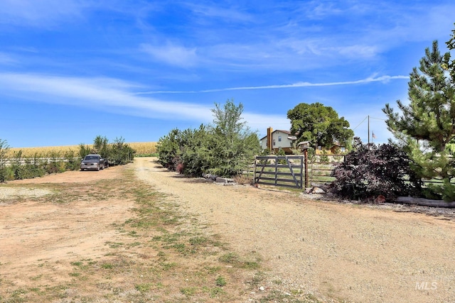 view of street with a gate, driveway, and a rural view