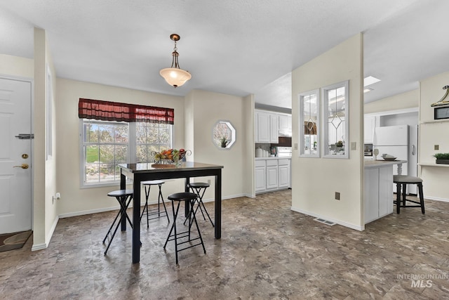 dining area featuring lofted ceiling, visible vents, and baseboards