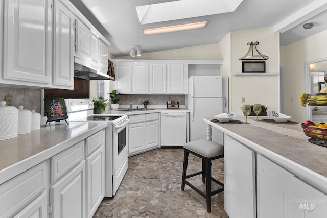 kitchen with lofted ceiling with skylight, white cabinets, decorative backsplash, white appliances, and stone finish flooring