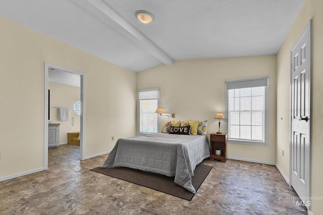 bedroom featuring lofted ceiling with beams, baseboards, multiple windows, and ensuite bathroom