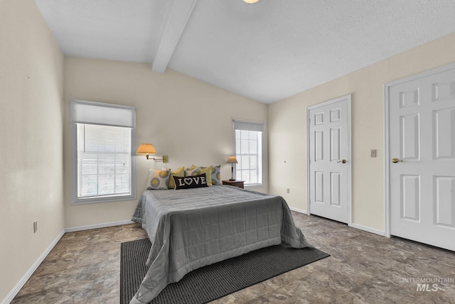bedroom featuring stone finish floor, vaulted ceiling with beams, and baseboards