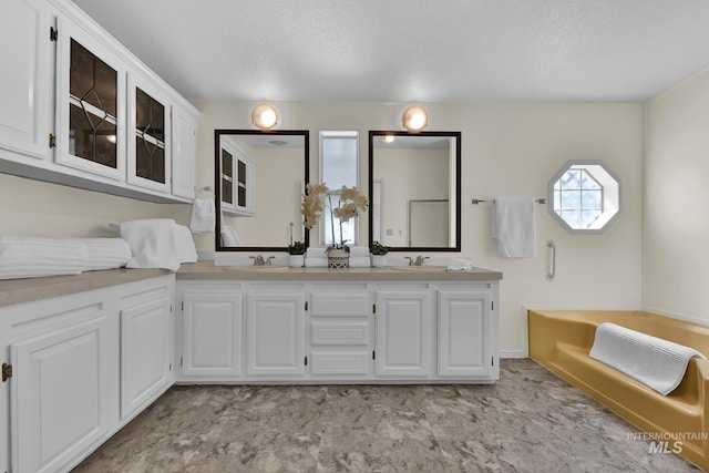 full bath with a textured ceiling, a bathing tub, and a sink