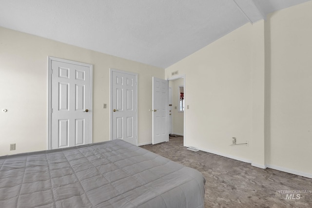 bedroom featuring baseboards, lofted ceiling, visible vents, and carpet