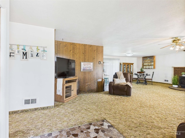 1929 S 2350 E, Malta, ID 83342 - living room featuring carpet flooring, wood walls, a ceiling fan, and a wood stove