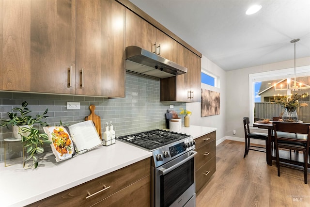 kitchen featuring high end range, decorative light fixtures, light hardwood / wood-style flooring, and tasteful backsplash