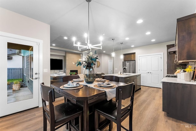 dining area featuring light hardwood / wood-style flooring, a notable chandelier, and sink