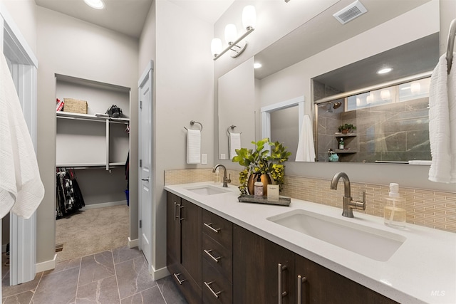 bathroom with tile patterned floors, vanity, a shower with door, and tasteful backsplash