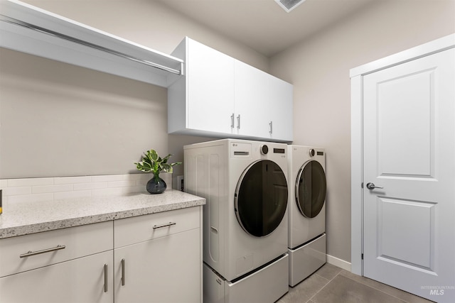 laundry area featuring cabinets, independent washer and dryer, and dark tile patterned floors