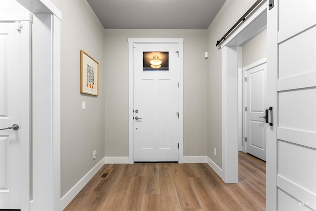 doorway to outside featuring a barn door and light hardwood / wood-style floors