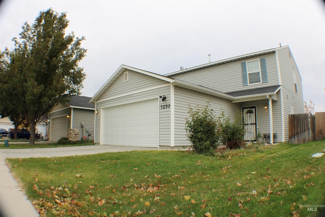 traditional-style home featuring a garage, concrete driveway, fence, and a front lawn