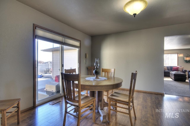 dining space with dark wood-type flooring and baseboards