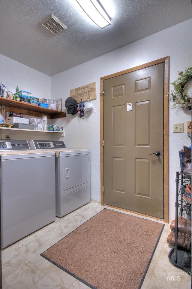 laundry area featuring a textured ceiling, laundry area, washer and clothes dryer, and visible vents