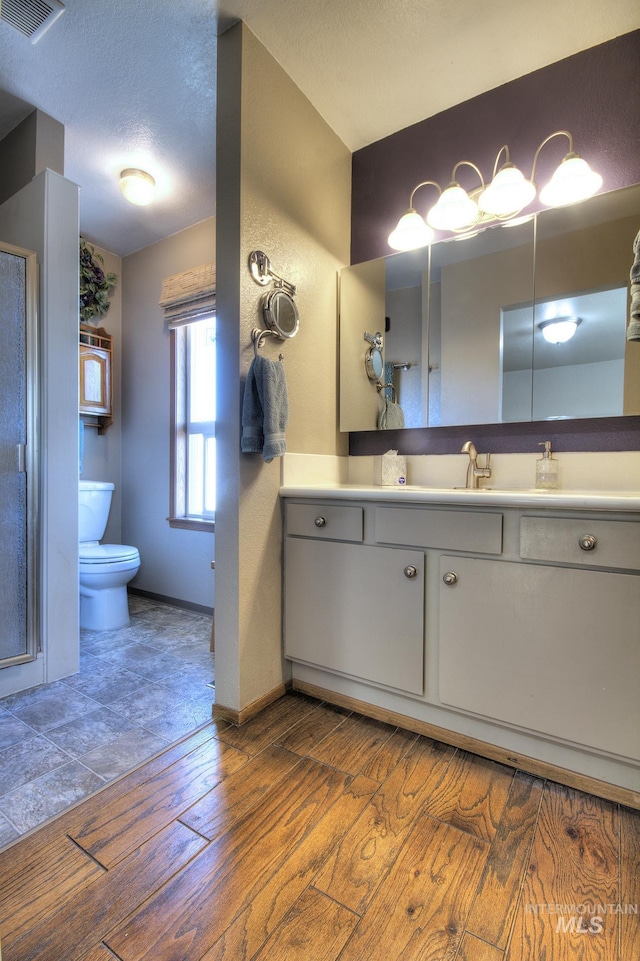 bathroom featuring visible vents, toilet, wood finished floors, a textured ceiling, and vanity