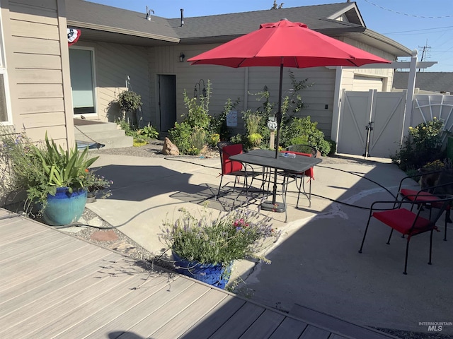 view of patio with outdoor dining area, fence, and a gate