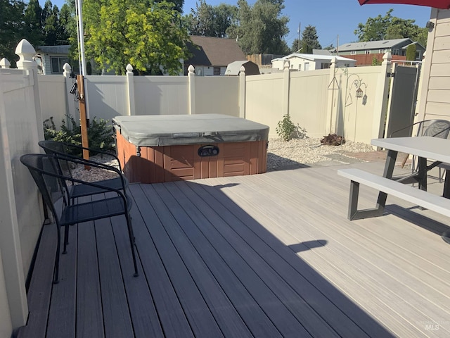 wooden deck with a hot tub and a fenced backyard