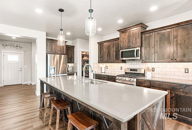 59 S Ravine Way, Nampa, ID 83687 - kitchen with appliances with stainless steel finishes, a sink, light wood-type flooring, dark brown cabinetry, and recessed lighting