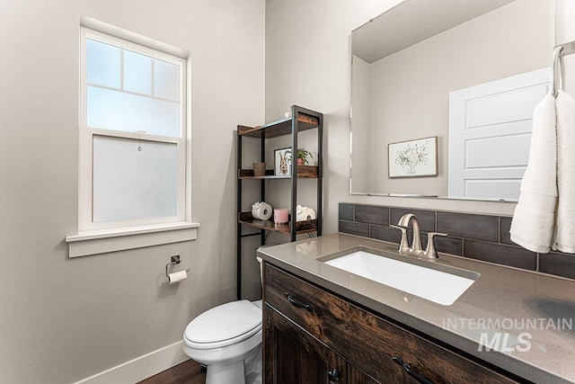 59 S Ravine Way, Nampa, ID 83687 - half bathroom featuring vanity, tasteful backsplash, toilet, baseboards, and wood finished floors