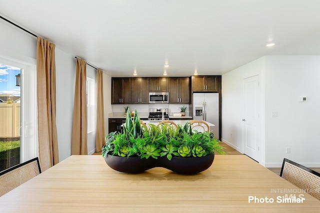 kitchen with baseboards, dark brown cabinetry, light countertops, recessed lighting, and appliances with stainless steel finishes