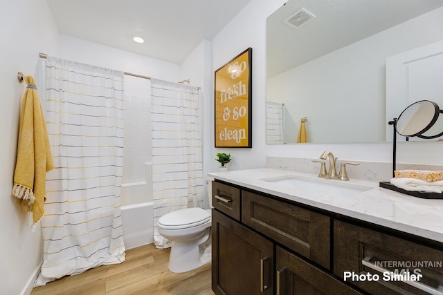 full bathroom featuring vanity, wood finished floors, visible vents, shower / bath combo, and toilet