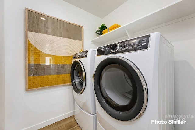 clothes washing area with baseboards, independent washer and dryer, wood finished floors, and laundry area