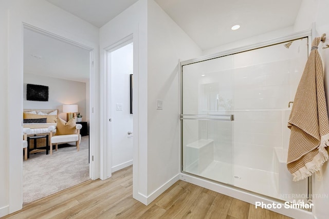 ensuite bathroom featuring a stall shower, ensuite bathroom, baseboards, and wood finished floors