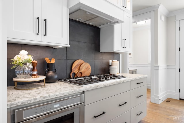 3051 S Sedgebrook Ln, Eagle, ID 83616 - kitchen featuring ventilation hood, stainless steel gas stovetop, wall oven, light wood-type flooring, and tasteful backsplash