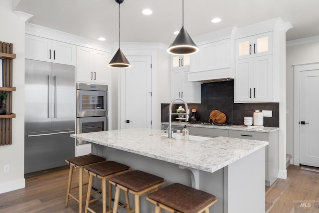 3051 S Sedgebrook Ln, Eagle, ID 83616 - kitchen featuring appliances with stainless steel finishes, wood finished floors, decorative backsplash, glass insert cabinets, and recessed lighting