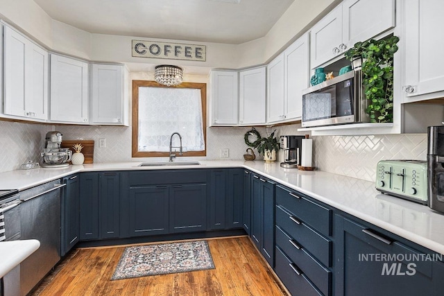 kitchen with white cabinetry, light countertops, light wood finished floors, and a sink