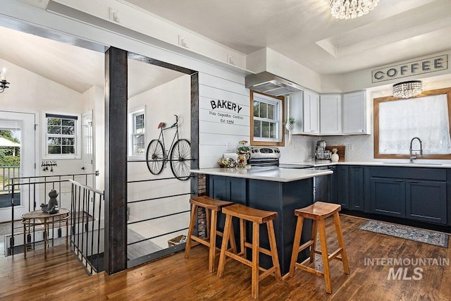 kitchen featuring dark wood finished floors, a sink, light countertops, a kitchen breakfast bar, and a notable chandelier