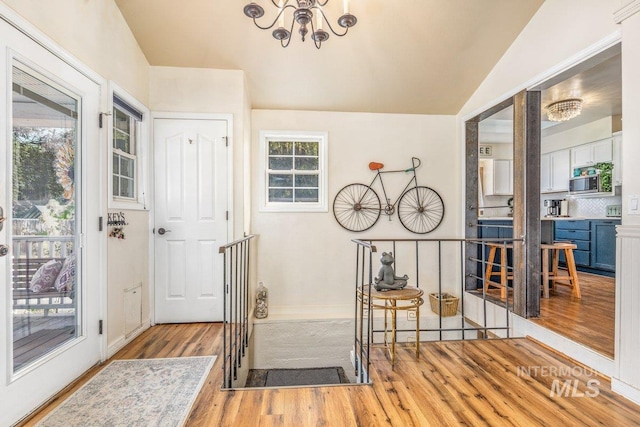 foyer featuring a chandelier, baseboards, lofted ceiling, and wood finished floors