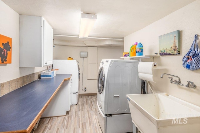 laundry room featuring a sink, washer and dryer, laundry area, and light wood finished floors