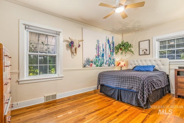 bedroom featuring visible vents, wood finished floors, baseboards, and ornamental molding