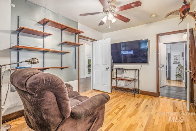 living room featuring hardwood / wood-style floors, a ceiling fan, and baseboards