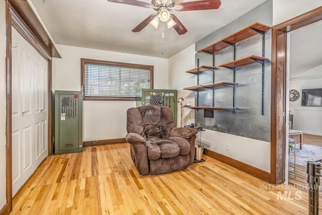 sitting room featuring light wood finished floors, baseboards, and ceiling fan