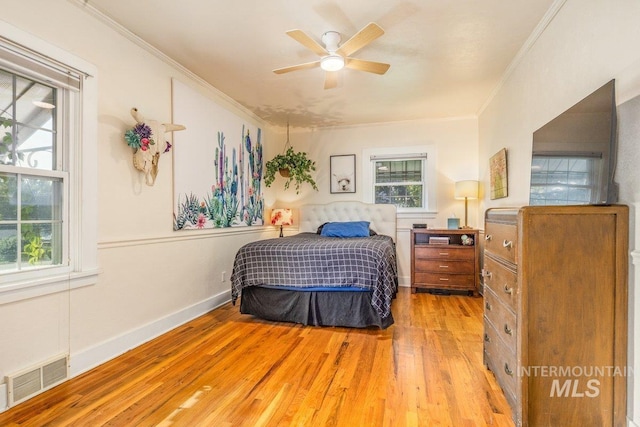 bedroom with visible vents, multiple windows, ornamental molding, and wood finished floors